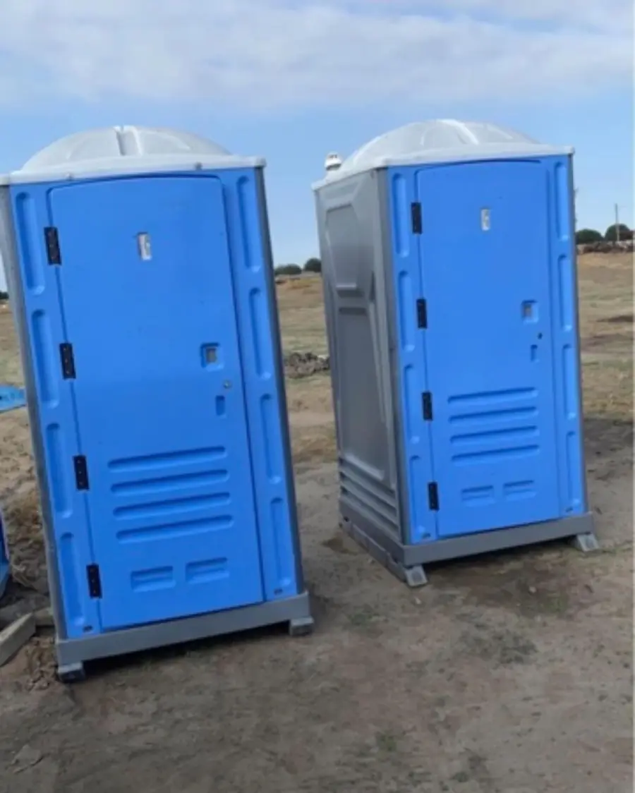 Blue standard porta potties on a dirt construction lot