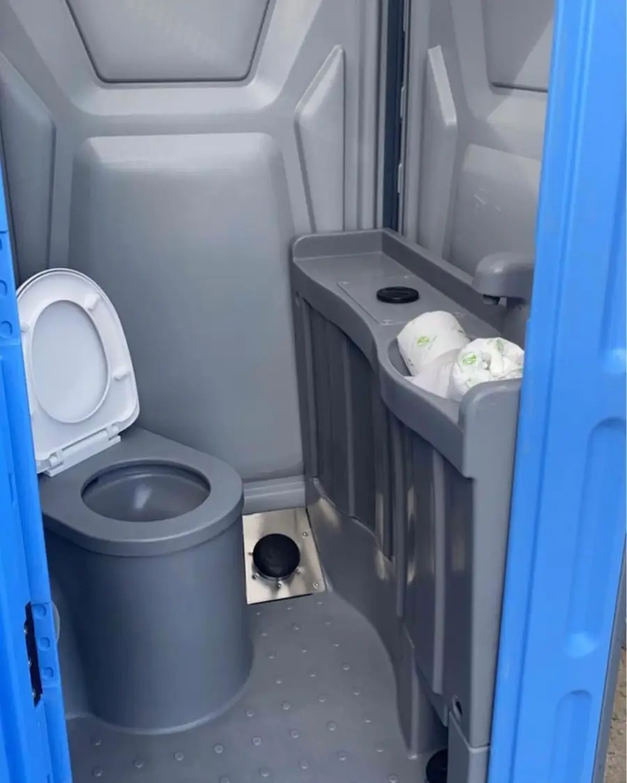 Inside a deluxe flushing porta potty with a sink counter
