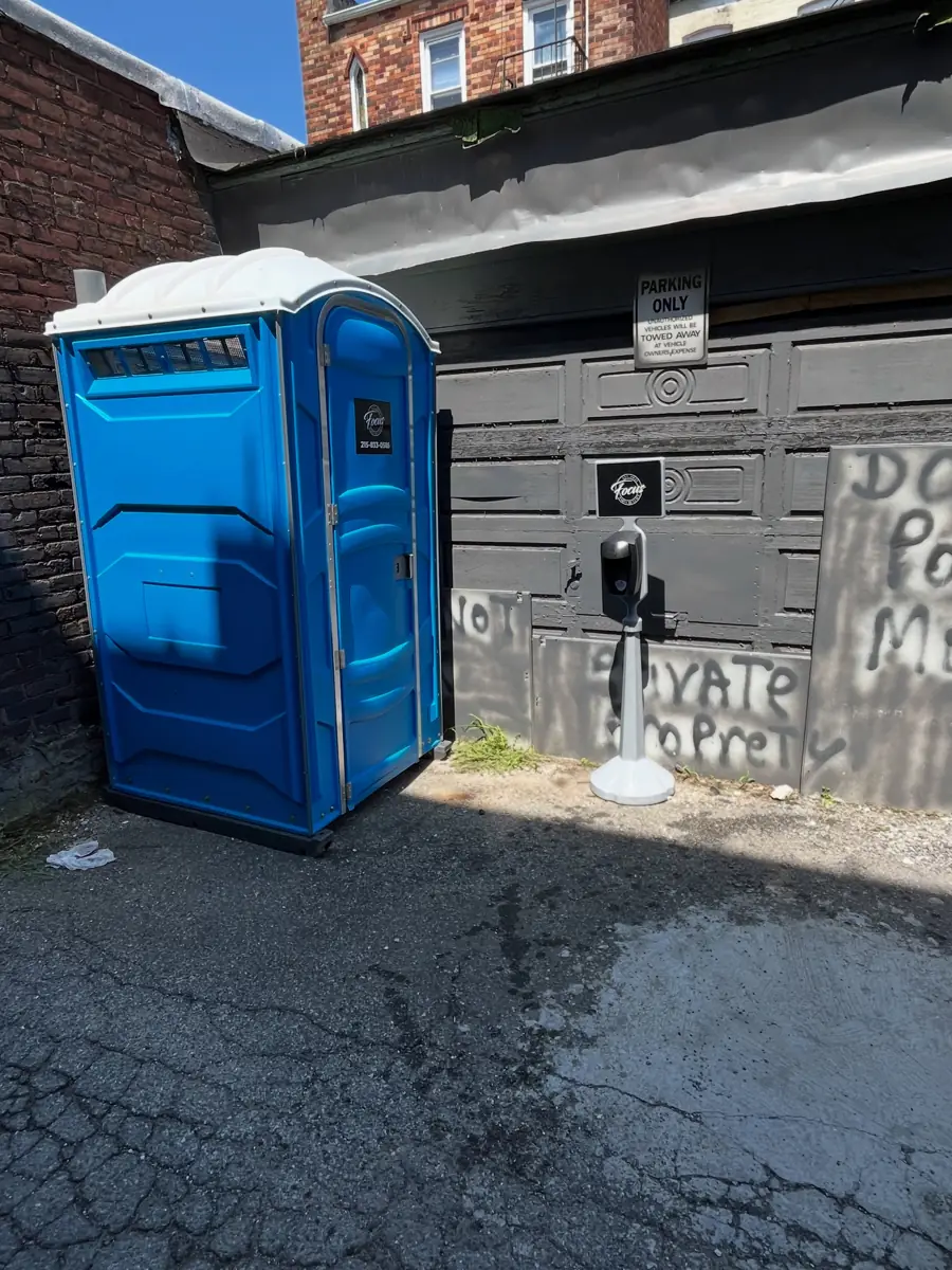 Blue porta potty beside a commercial building